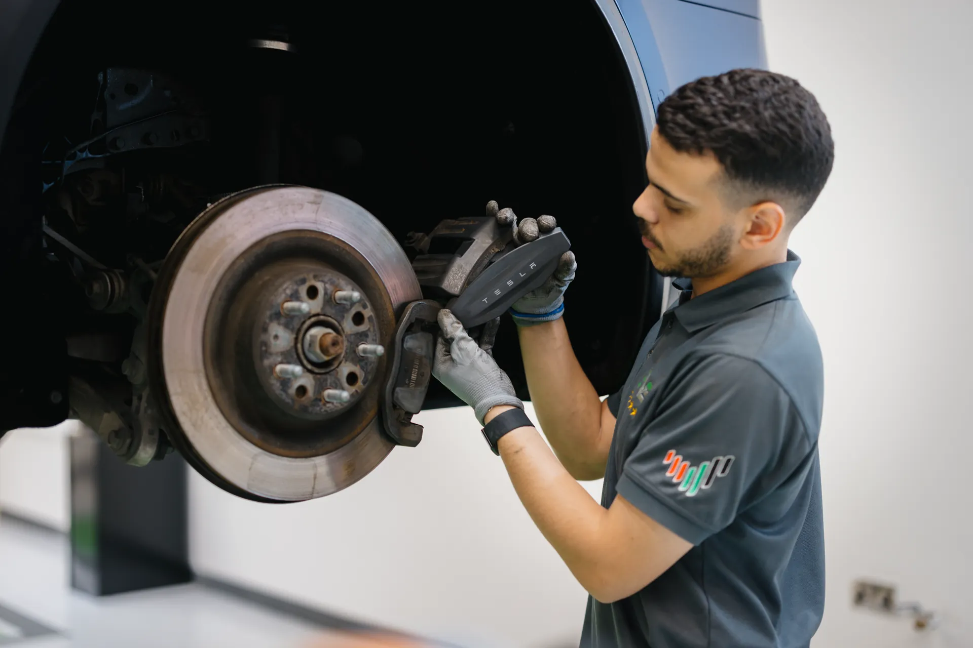 An EVS technician replacing a brake component on an electric car